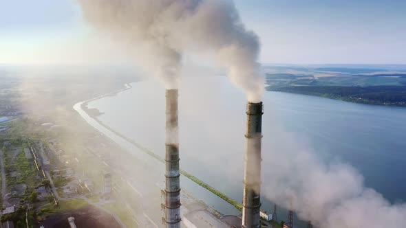 Aerial view of coal power plant high pipes with black smokestack polluting atmosphere.