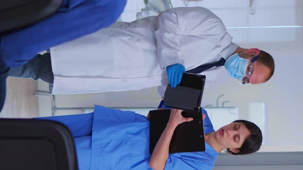 Dental Specialist Speaking with Assistant Standing in Waiting Room