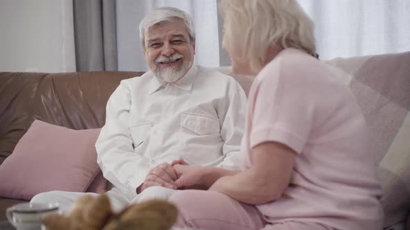 Portrait of Cheerful Caucasian Senior Man and Mature Woman Talking and Laughing at Home, Happy