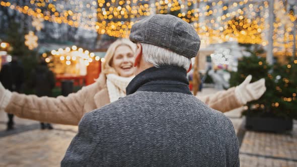 Happy Senior Woman and Man Hugging After Separation Enjoying Date Outdoor at Christmas City Square