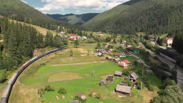 Aerial Shot of Train Passing Through Village in Carpathian Mountains in Ukraine