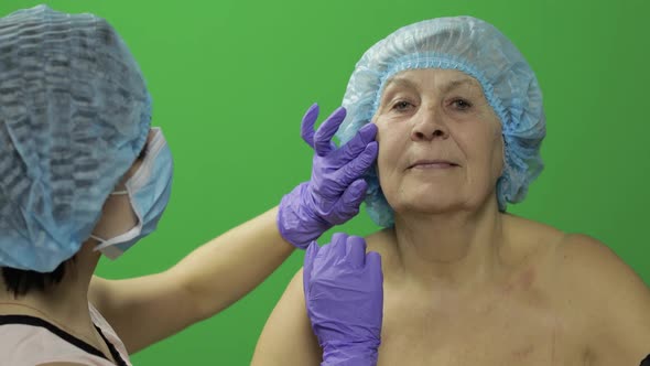 Smiling Elderly Female in Protective Hat. Plastic Surgeon Checking Woman Face