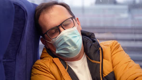 Tired Millennial Man in Medical Mask and Misted Glasses Sitting Near Window in Metro Train in City