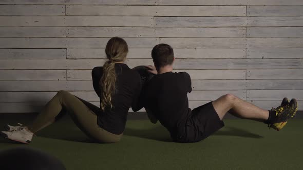 Couple passing medicine ball as they balance