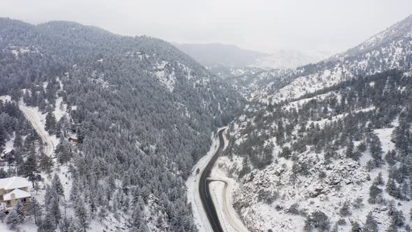 Aerial reveal forward of Boulder Canyon Drive in Colorado during the winter as cars drive down icy r