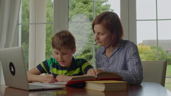 Young Adult Mother Making Online Homework with School Child at Home