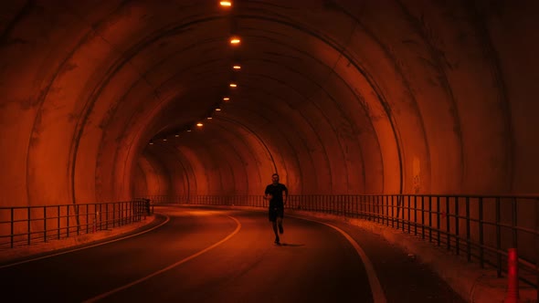 Male athlete running fast through empty tunnel