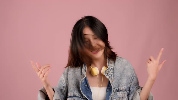 Happy pretty Asian teenager girl dancing and flicking hair on pink background, Slow motion shot.