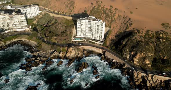 Aerial orbit of a building between the dunes of Concon and the waves of the pacific ocean in Chile.