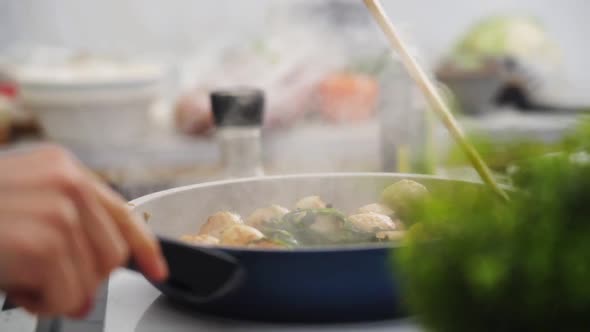 Crop person stirring vegetable stew with mushrooms