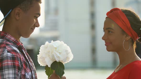 Smiling Black Teen Boy Presenting Beloved Girl Bunch of Flowers, Birthday Gift