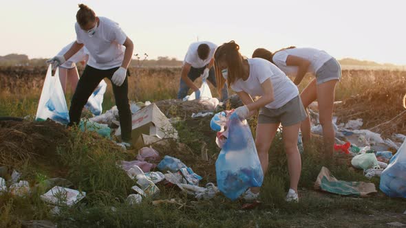 Group of Eco Volunteers Cleaning Up Area of Dump Near the Field During Sunset Slow Motion