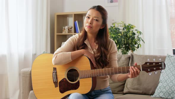 Young Woman with Guitar Videoblogging at Home