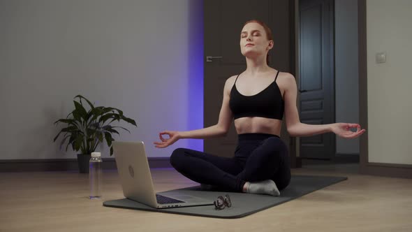 The Girl Presses the Play Button on the Laptop and Begins to Meditate