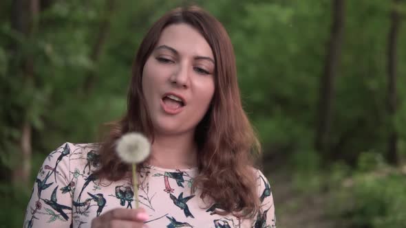 Girl Blowing Dandelion in the Forest