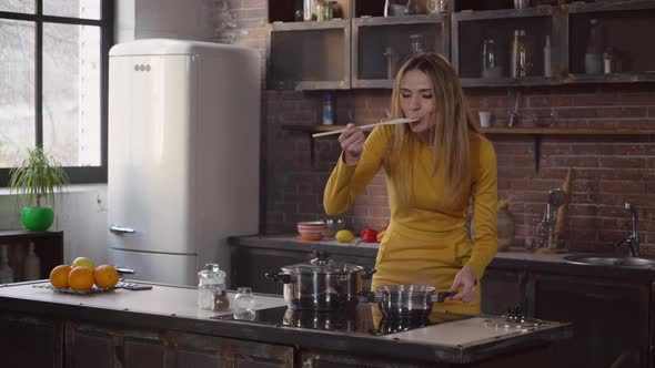 Attractive Female Cooks Lunch with Smile in House.