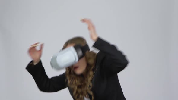 Young Woman with Virtual Reality Glasses on Her Head on Gray Background at Studio.