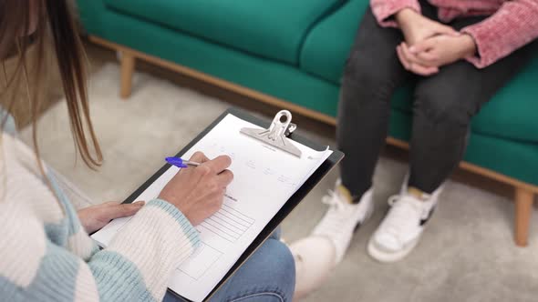 Psychologist Writing Notes During Therapy Session with Nervous Anxious Teenager Girl Who Needs