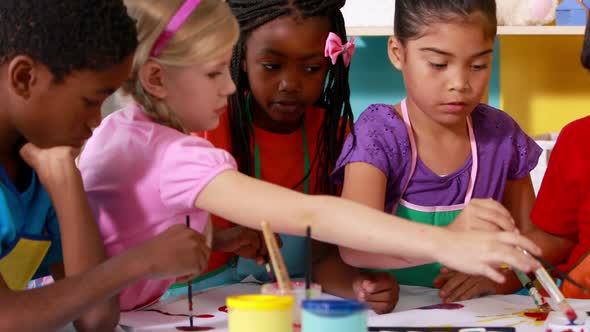 Preschool class painting at table in classroom