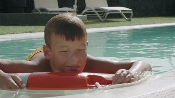 Today he is too lazy to swim. Relaxed boy floating on safety ring in the pool