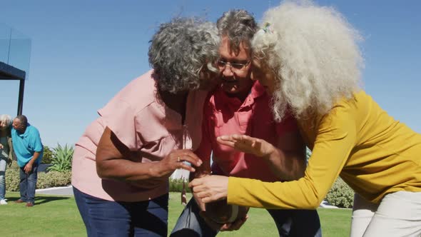 Happy senior diverse people playing rugby in garden at retirement home