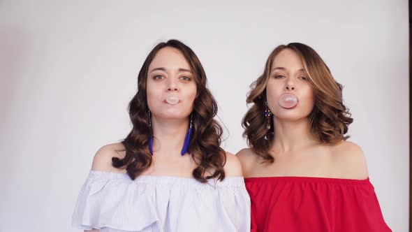 Twin Girls Blowing Chewing Gum Into Bubbles.