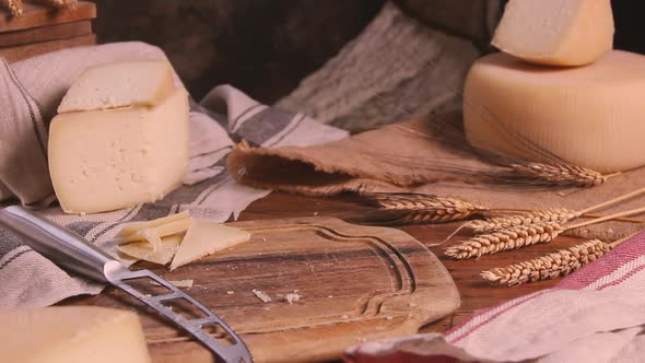 Women hands put pieces of fresh homemade cheese on a wooden board close up