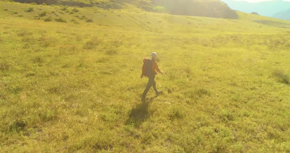 Flight Over Backpack Hiking Tourist Walking Across Green Mountain Field. Huge Rural Valley at Summer