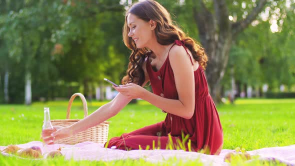 Happy Woman with Smartphone on Picnic at Park