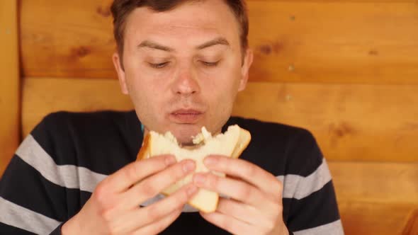 a Man Bites and Eats a Sandwich Made of White Bread