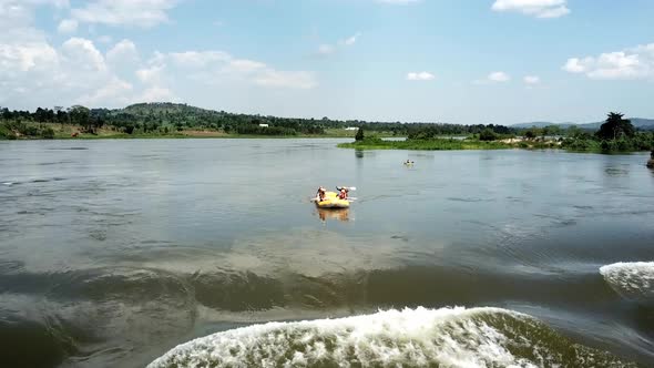 Drone front view of a yellow boat descending and capsizing at a waterfall on the Nile River in Jinja