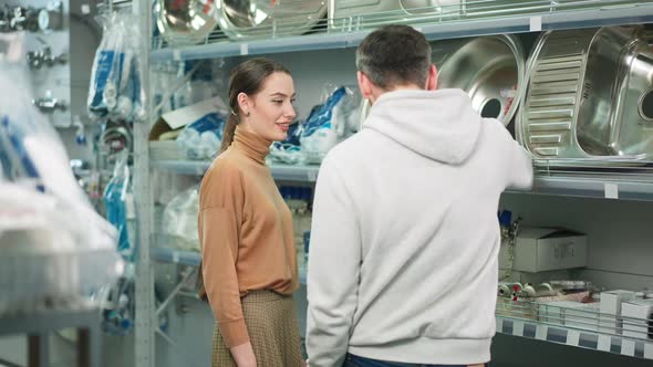 Young Confident Woman Discussing Purchase of New Sink in Hardware Store with Man