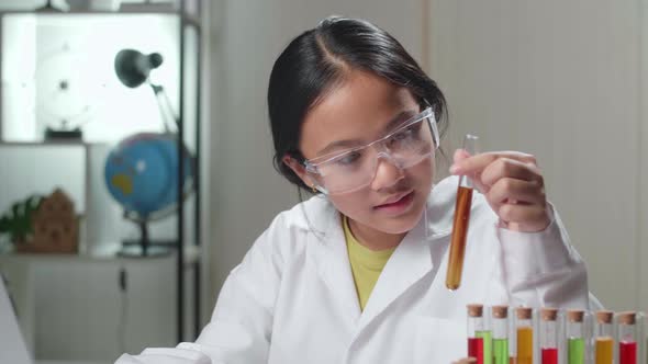 Young Asian Scientist Girl Holding Test Tube And Work With Laptop. Child Learn With Interest