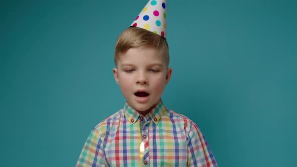 Kid in Party Hat Blowing Out Birthday Candle in Slow Motion