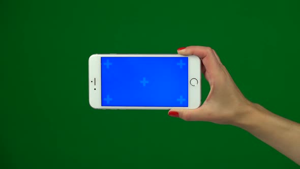 Hand Holding a Blue Screen Smartphone Over a Green Screen