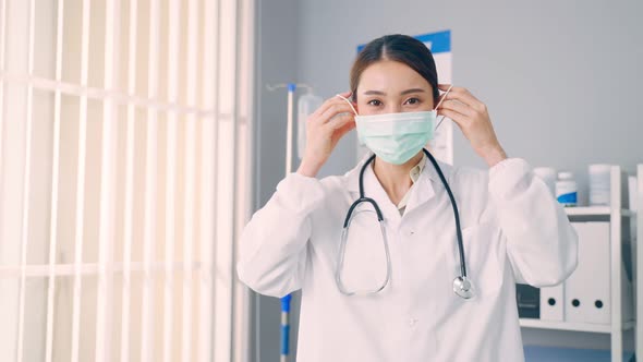 Portrait of Asian female doctor remove protective surgical face mask.