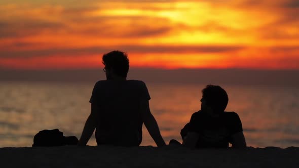 People Sit in the Beach in Sunset Light