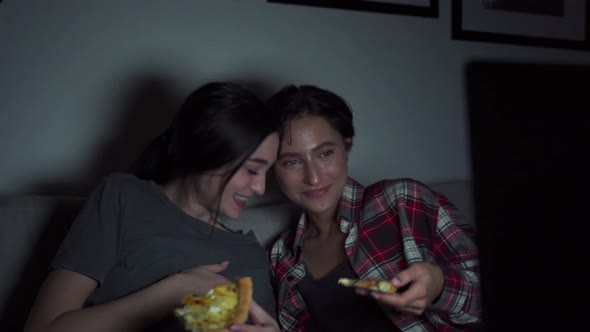 Two Happy Young Girls Having Fun Eating Pizza Watching Tv at Home Party Late