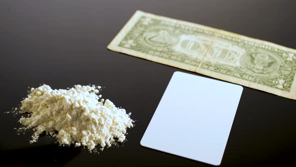 Lines of cocaine and a dollar bill. Cocaine lines shots on a black table glass.