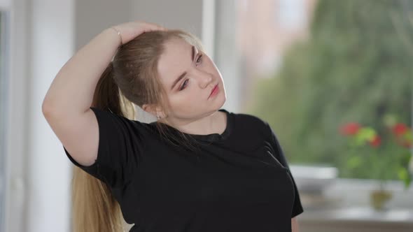 Charming Overweight Caucasian Woman Stretching Neck Exercising at Home in the Morning