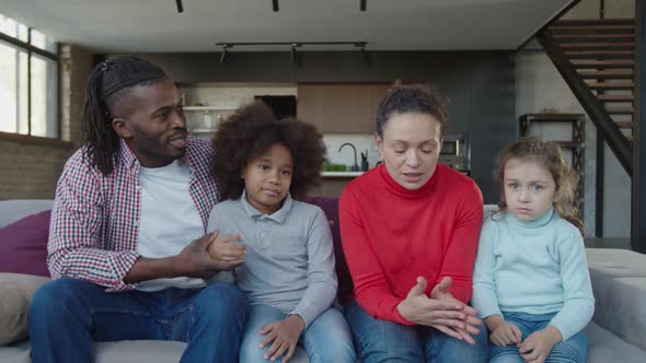 Portrait of Positive Multiethnic Family with Two Little Daughters Bonding in Domestic Room