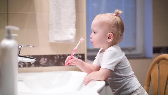 Little girl with a toothbrush in front of a bathroom mirror