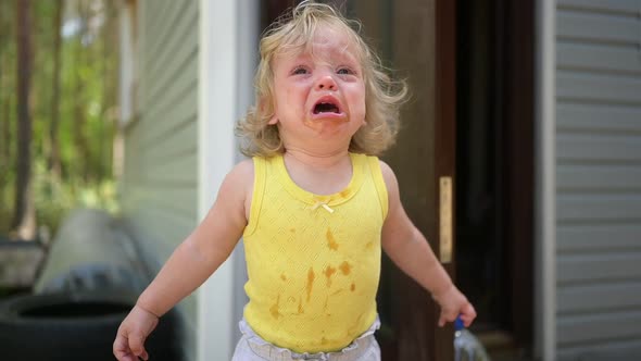 Close Up Portrait of Little Funny Cute Blonde Girl Child Toddler in Yellow Dirty Bodysuit Crying