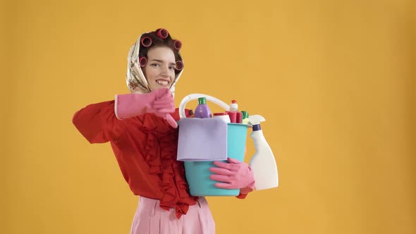 A Woman Holds a Bucket of Cleaning Products in Her Hands and Shows a Dislike