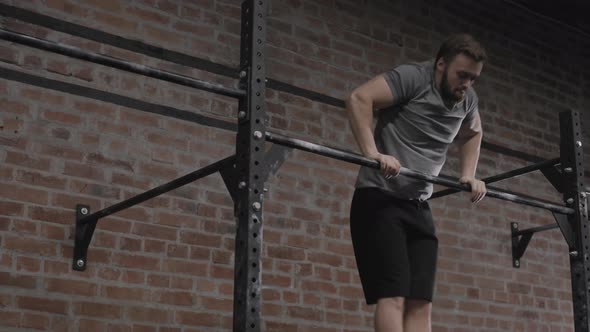 Young Sporty Man Exercising on Horizontal Bar in Gym