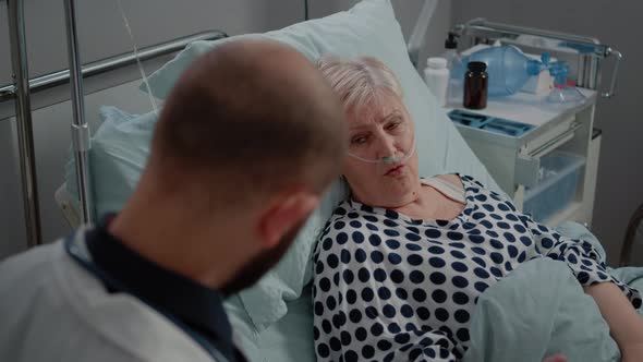 Retired Woman with Nasal Oxygen Tube Talking to Doctor