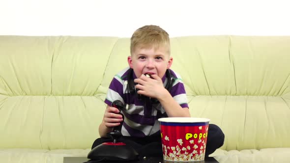 Boy Plays Joystick Online Game and Eats Popcorn, Slow Motion