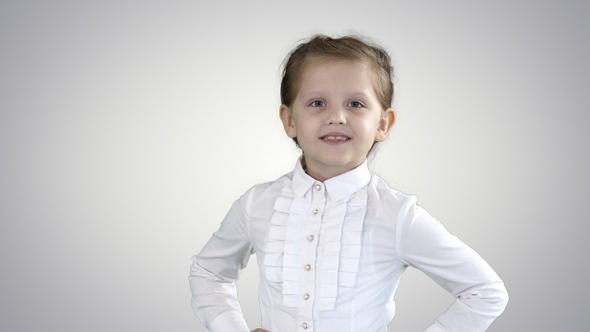 Cute little girl in white dress posing on camera on gradient