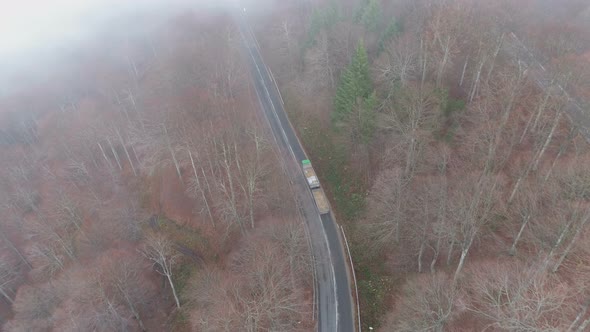 Heavy Loaded Truck Driving Uphill in Mountain Forest in Misty Autumn Day, Drone View