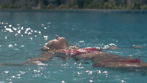 Slim Lady in Trendy Red Bikini Swims in Crystal Blue Pool